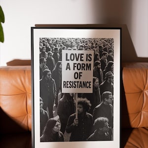 Pu&ograve; includere: Stampa in bianco e nero incorniciata raffigurante una folla. Un cartello con la scritta "LOVE IS A FORM OF RESISTANCE" &egrave; tenuto da una persona. La stampa &egrave; esposta su un divano in pelle marrone.