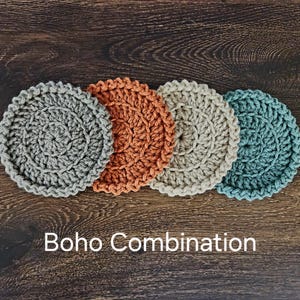May include: Four crocheted coasters in a boho style. The coasters are in shades of gray, orange, beige, and blue.