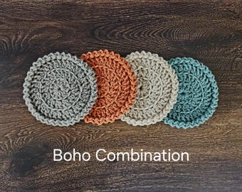 May include: Four crocheted coasters in a boho style. The coasters are in shades of gray, orange, beige, and blue.