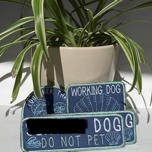 May include: Three rectangular and semi-circular embroidered patches in dark blue with light blue stitching. The patches feature the text WORKING DOG, DO NOT PET, and TOGETHER, along with illustrations of waves and a seashell motif.