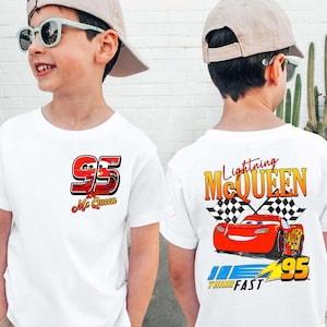 May include: White t-shirt featuring Lightning McQueen from the Cars movie. The front displays the number 95 and the words "McQueen". The back has a graphic of McQueen, a checkered flag, and the text "Lightning McQueen" and "Think Fast".