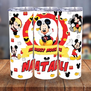 May include: White tumbler featuring Mickey Mouse illustrations. The design includes Mickey Mouse in various poses, a red and yellow circular frame, and the text "MICKEY MOUSE" and "NAATALI" in red. The tumbler has a silver lid.