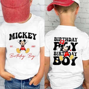 Op de afbeelding: Wit T-shirt met Mickey Mouse-ontwerp. De voorkant toont "Mickey" en "Birthday Boy". De achterkant van het shirt heeft "Birthday Boy" met Mickey Mouse en het nummer 13.