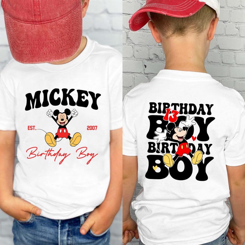 Op de afbeelding: Wit T-shirt met Mickey Mouse-ontwerp. De voorkant toont "Mickey" en "Birthday Boy". De achterkant van het shirt heeft "Birthday Boy" met Mickey Mouse en het nummer 13.
