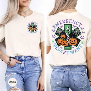 May include: Cream-colored t-shirt featuring a Halloween-themed design. The front displays a small emblem with pumpkins and the text "Emergency Department." The back showcases a larger design with pumpkins, bats, spiderwebs, and the same text. The shirt is made of a soft material.