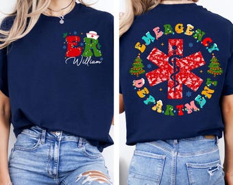 May include: Navy blue t-shirt with a festive ER design on the front, featuring a nurse's hat and the name "William." The back displays "EMERGENCY DEPARTMENT" around a red medical symbol with Christmas tree accents.
