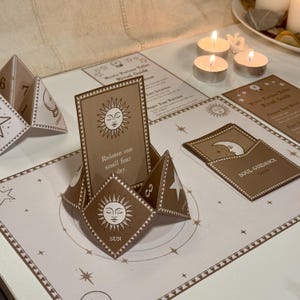 Op de afbeelding: Een bruin en wit orakelkaartensets met een zonnesymbool en de tekst "Release one small fear a day." en "SUN". De kaarten zijn in een cirkel op een bruin en wit tafel met kaarsen en andere orakelkaarten gerangschikt.