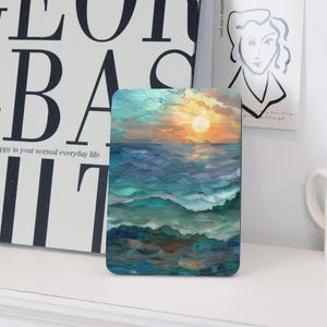 Könnte beinhalten: Rechteckiger Untersetzer mit einem abstrakten Ozean-Sonnenuntergang-Design. Das Kunstwerk verwendet Blau-, Türkis- und Grüntöne für das Wasser sowie Orange und Gelb für Sonne und Himmel. Der Untersetzer ist ein dekorativer Artikel.