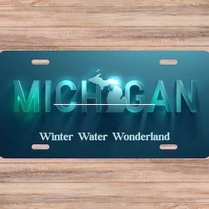 以下が含まれることがあります： 「MICHIGAN」の3D文字、地図の輪郭、そして「Winter Water Wonderland」というフレーズが特徴の、ターコイズ色のナンバープレート。プレートには取り付け用の4つのスロットがあります。