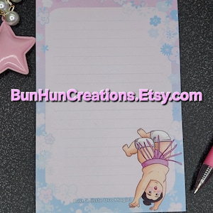 May include: A lined notepad with a sumo wrestler illustration. The notepad has a light blue and pink floral border and the text "Just a little Ura Magic!". The Etsy shop name "BunHunCreations.Etsy.com" is also visible.