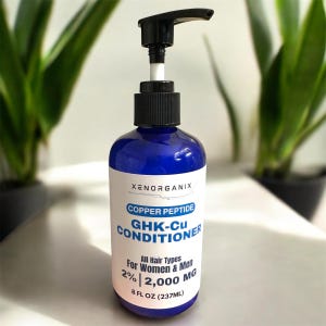 Puede incluir: Una botella azul de acondicionador GHK-Cu Xenorganix con un dispensador de bomba negro. La etiqueta dice "Copper Peptide" y "All Hair Types For Women & Men". La botella contiene 237 ml de producto.