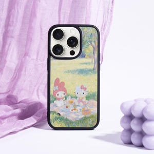 May include: A black phone case featuring a picnic scene with cartoon characters. The case has a colorful design with a black border. A lavender-colored bubble candle is next to the phone case.