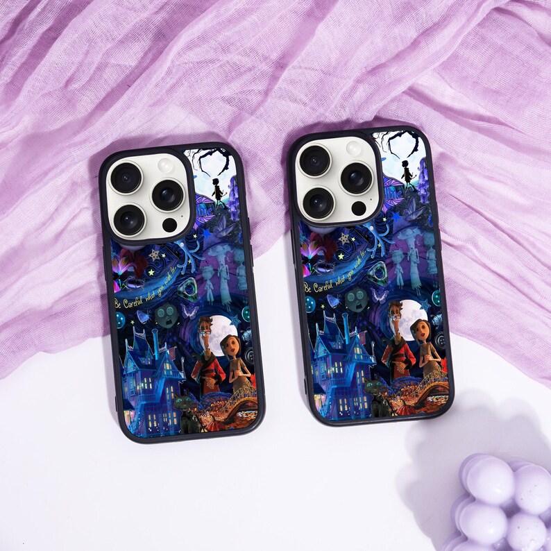 May include: Two black phone cases with a colorful illustration featuring a spooky house, characters, and the text "Be Careful what you wish for". The cases have a dark blue, purple, and white color scheme.