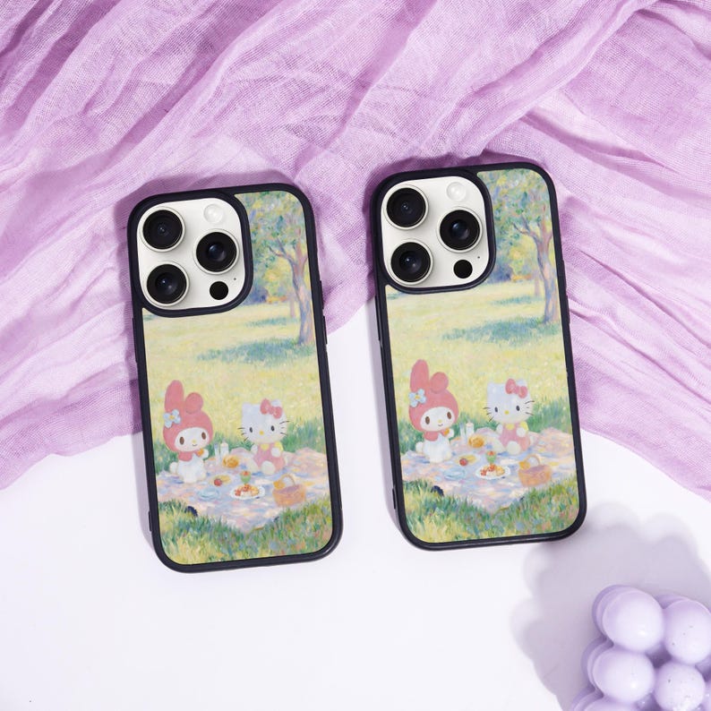 Puede incluir: Dos fundas para tel&eacute;fono con bordes negros. Cada funda presenta una escena de picnic con personajes de dibujos animados, ambientada en un parque con &aacute;rboles. Las fundas est&aacute;n sobre una superficie blanca con una tela morada.