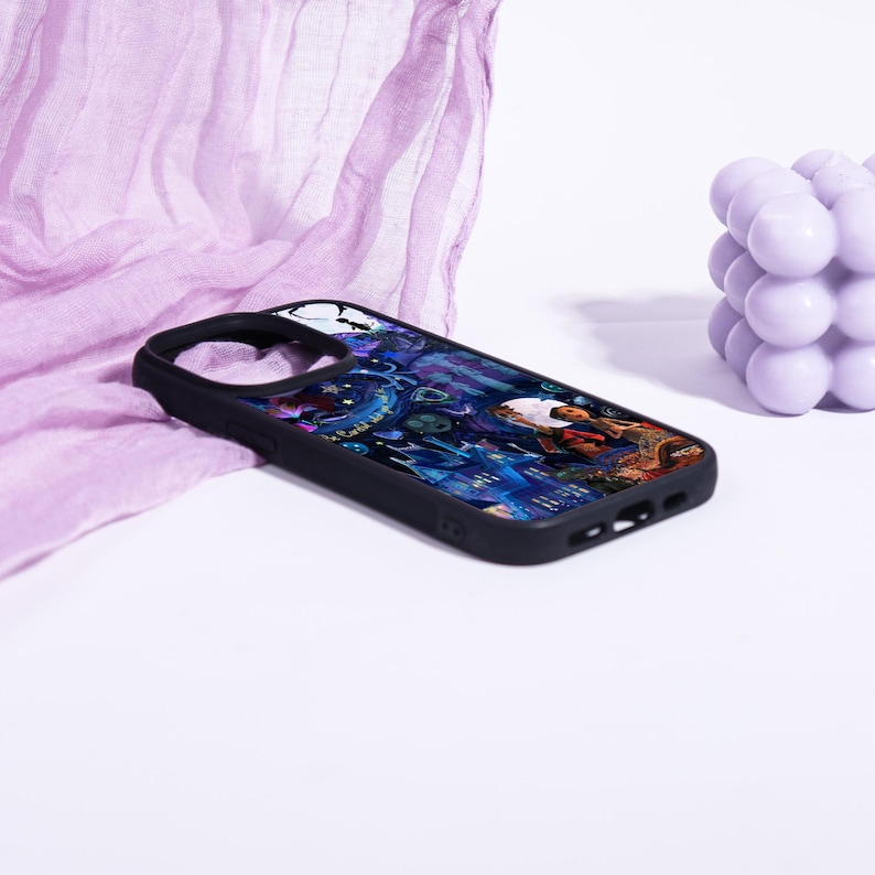 May include: Black phone case with a colorful illustration featuring a person, buildings, and other elements. The case has a black border and a cutout for the camera. The design is set against a dark blue and purple background.