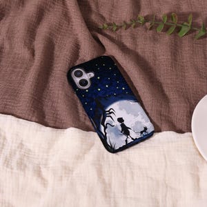 May include: A black phone case featuring a whimsical illustration of a silhouetted figure, a cat, and a tree against a full moon and starry night sky. The top of the case has a dark blue background with yellow stars.