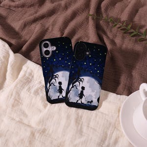 May include: Two black phone cases with a nighttime scene featuring a full moon, silhouettes of figures, and a starry sky. The cases have a dark blue and black color scheme, with a whimsical, fantasy theme.