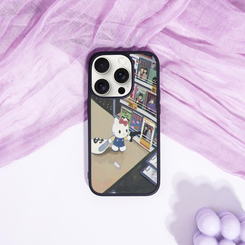 May include: Black phone case featuring a colorful illustration of Hello Kitty in a blue dress, holding a gun and a bag of money. The background depicts a store with various items on display. The case has a black border and a camera cutout.