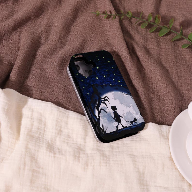 May include: A black phone case featuring a whimsical illustration of a person and a cat walking towards a large moon under a starry night sky. The case has a silver border and a dark blue background.