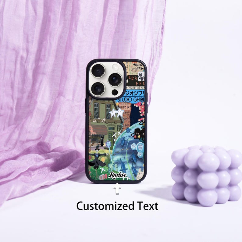 May include: A black phone case with a colorful collage design featuring illustrations and Japanese text. The case has a black border and a cutout for the camera. The text "Jindar" is visible on the case. The words "Customized Text" are below the phone case.