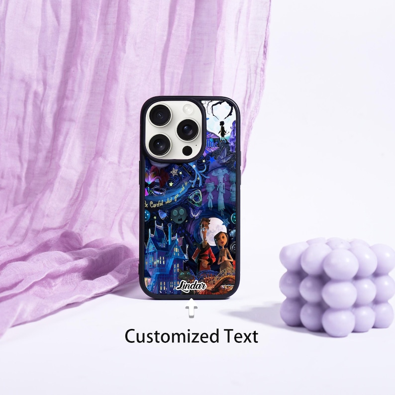 May include: Black phone case with a colorful illustration featuring a full moon, a spooky house, and two characters. The case has the text "Lindar" and "Customized Text". A lavender bubble candle sits to the right.