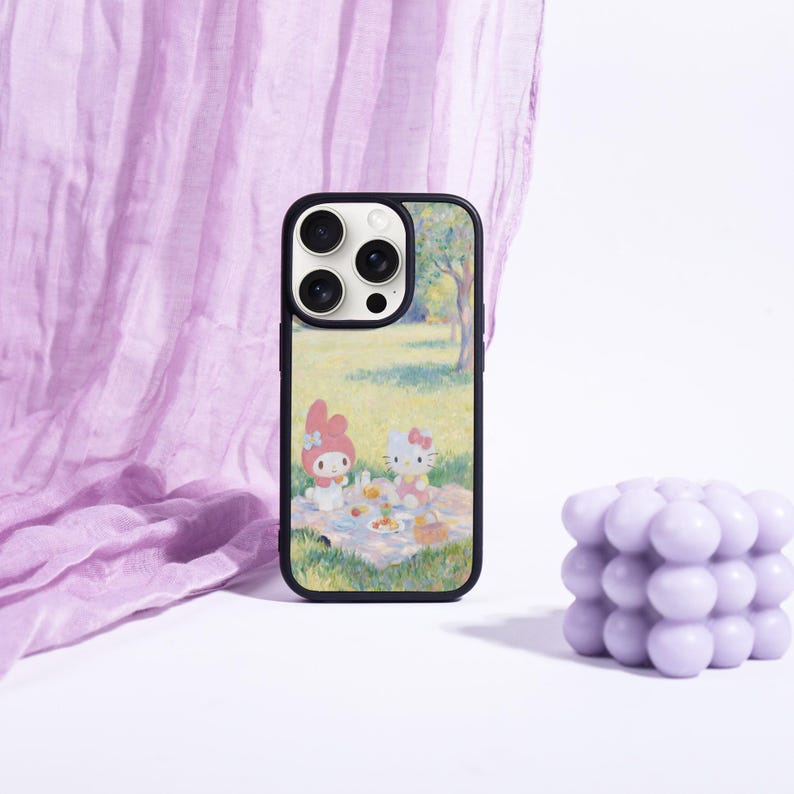 May include: A black phone case featuring a picnic scene with cartoon characters. The case has a colorful design with a black border. A lavender-colored bubble candle is next to the phone case.