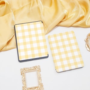 K&ouml;nnte beinhalten: Zwei E-Reader-H&uuml;llen mit gelbem und wei&szlig;em Gingham-Muster. Die H&uuml;llen sind aus einem weichen, strapazierf&auml;higen Material gefertigt und sch&uuml;tzen Ihren E-Reader vor Kratzern und St&ouml;&szlig;en.