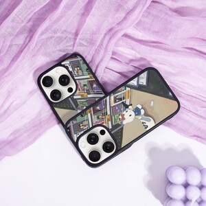 May include: Two black phone cases with a colorful cartoon design. One case features a comic book-style illustration, while the other showcases a cartoon character with a money bag. The cases are set against a purple fabric background.