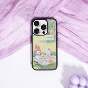 Puede incluir: Funda de tel&eacute;fono negra con una colorida ilustraci&oacute;n de una escena de picnic con dos personajes de dibujos animados. La funda tiene un borde negro y un recorte para la c&aacute;mara. El fondo es una tela morada clara.