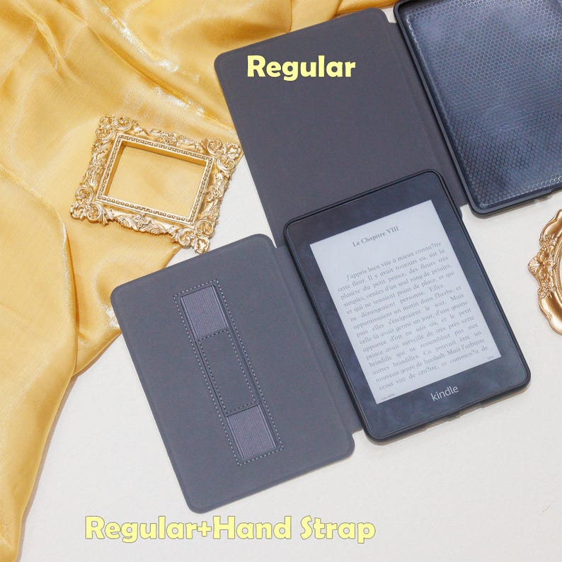 K&ouml;nnte beinhalten: Ein grauer Kindle E-Reader mit schwarzem Cover und einem Handriemen. Der Bildschirm zeigt den Text "La Chapitre VII" und das Wort "kindle".