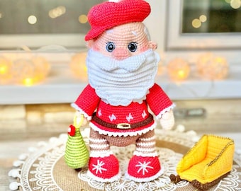 May include: A handmade crochet Santa Claus doll. The doll wears a red hat, jacket, and boots, and has a white beard. It holds a green Christmas tree. A yellow sleigh is next to the doll. The doll is on a decorative round mat.