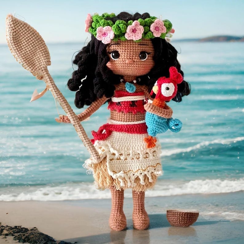 Op de afbeelding: Een gehaakte pop van Moana uit de Disney-film Vaiana. De pop draagt een rood-wit topje, een bruine rok en een bloemenkrans. Ze houdt een blauw-rode gehaakte papegaai vast.
