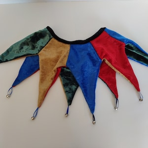 K&ouml;nnte beinhalten: Eine mehrfarbige Narrenkappe mit Gl&ouml;ckchen. Die Kappe ist aus Samt und hat f&uuml;nf Zacken. Die Farben sind Gr&uuml;n, Gold, Blau und Rot.