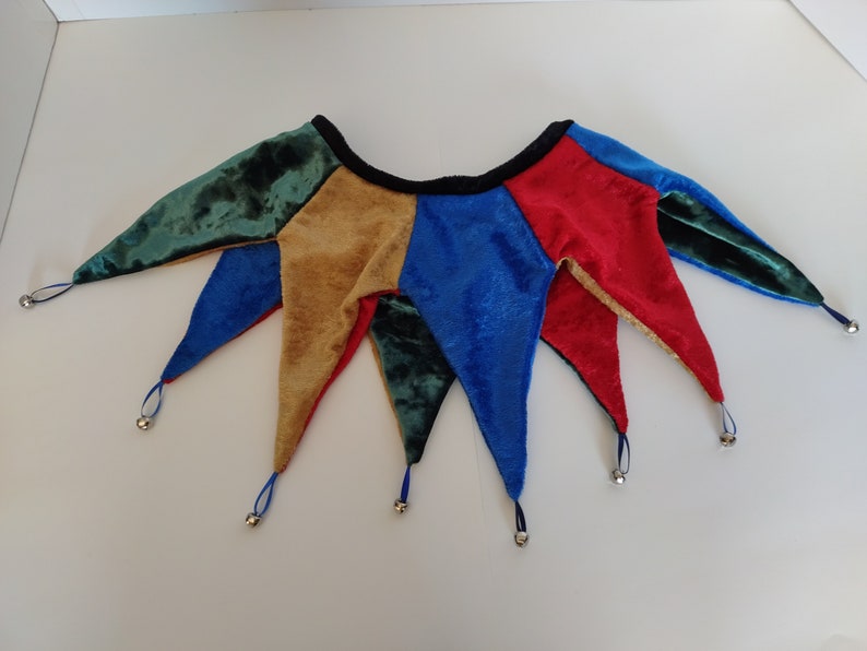 K&ouml;nnte beinhalten: Eine mehrfarbige Narrenkappe mit Gl&ouml;ckchen. Die Kappe ist aus Samt und hat f&uuml;nf Zacken. Die Farben sind Gr&uuml;n, Gold, Blau und Rot.