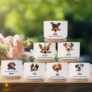May include: White ceramic pots with dog portraits, each on a wooden coaster. The dogs' names are printed below their images: Duke, Bella, Molly, Hunter, Luna, Milo, and Duke. The text "Always Remembering in my heart" is also printed on each pot.
