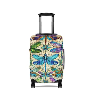 May include: A patterned suitcase featuring a dragonfly design. The design includes dragonflies in blue, green, purple, and yellow, set against a cream background. The suitcase has a black handle and wheels.