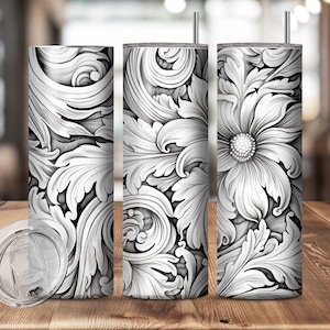 May include: Three stainless steel tumblers with a floral and leaf design in black and white. One tumbler has a clear lid and straw. The design features detailed, swirling patterns and a central flower with a textured center.