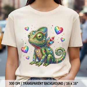 May include: Cream-colored t-shirt featuring a colorful, bejeweled chameleon with rainbow heart accents. The chameleon has green, blue, and yellow scales and wings. The text at the bottom reads "300 DPI / TRANSPARENT BACKGROUND / 16 x 16".