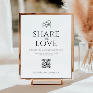 Könnte beinhalten: Ein rechteckiges Schild mit goldenem Rahmen, das den Text "SHARE THE LOVE" in schwarzer Schrift zeigt. Das Schild enthält einen QR-Code und wird von einem goldenen Ständer getragen. Ideal für Hochzeiten oder besondere Anlässe.