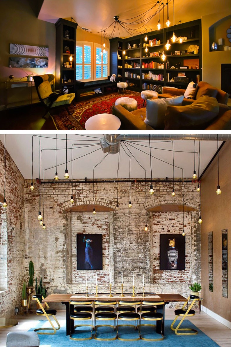 May include: Two rooms with exposed brick walls and a unique lighting fixture made of multiple Edison bulbs hanging from black cords. The first room is a living room with a bookshelf, a couch, and a chair. The second room is a dining room with a long wooden table and chairs.