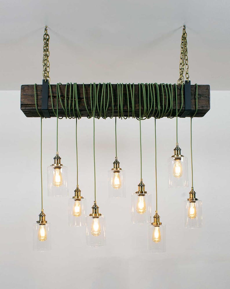 May include: A rustic wooden beam chandelier with nine clear glass pendant lights and green cords. The lights are suspended from the beam with brass chains and fixtures.