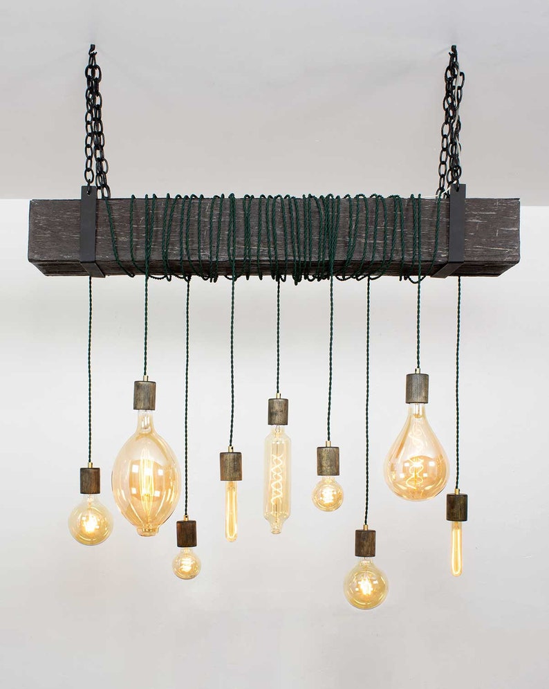 May include: A rustic wooden beam chandelier with nine hanging light bulbs. The bulbs are Edison style with a warm glow. The cords are black and the beam is dark brown.