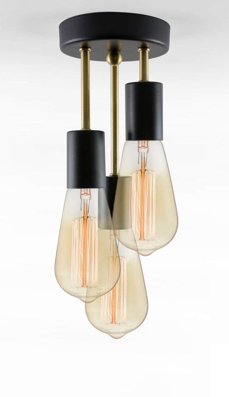 May include: A black and gold ceiling light fixture with three Edison bulbs. The fixture has a round black canopy and three black cylindrical shades.
