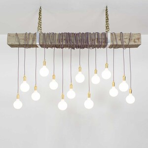 May include: A rustic wooden beam chandelier with 15 white light bulbs hanging from purple cords. The cords are wrapped around the beam and secured with metal brackets.