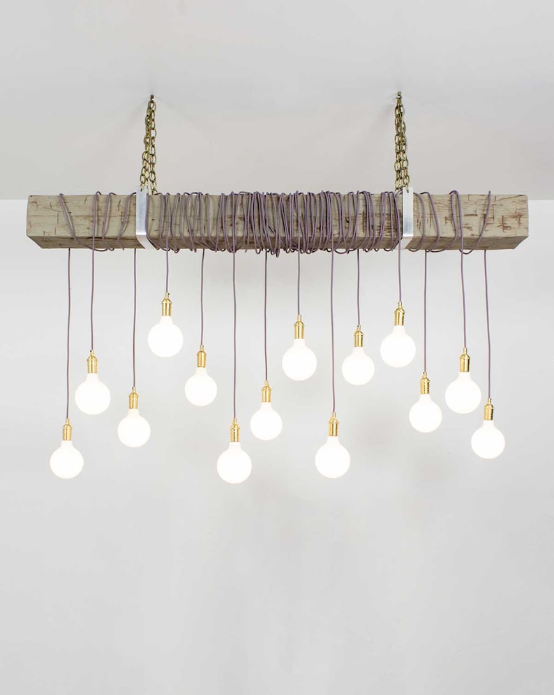 May include: A rustic wooden beam chandelier with 15 white light bulbs hanging from purple cords. The cords are wrapped around the beam and secured with metal brackets.