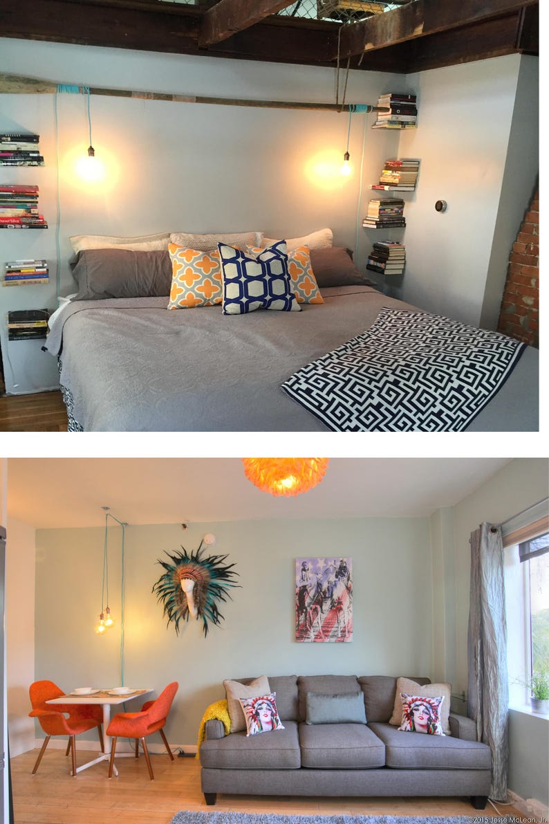 May include: A bedroom with a gray bed, a gray blanket with a geometric pattern, and two pillows with geometric patterns. There are bookshelves on the wall with books and a light fixture hanging from the ceiling.