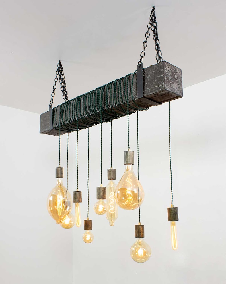 May include: A rustic wooden chandelier with a dark gray finish and multiple Edison bulbs hanging from it. The bulbs are suspended from the wood beam by green cords.