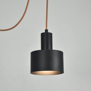 May include: A black pendant light with a cylindrical shade and a copper cord.