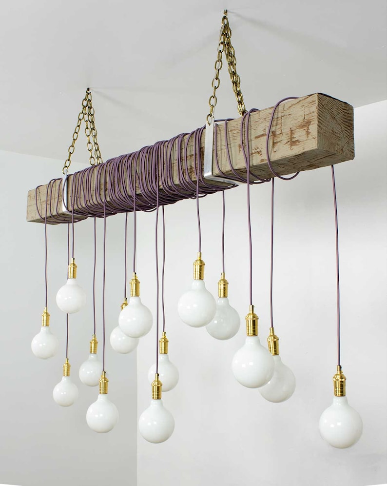 May include: A rustic wooden beam chandelier with multiple white globe light bulbs hanging from purple cords. The chandelier is suspended from the ceiling with brass chains.