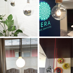 May include: Four different overhead light fixtures with exposed bulbs. The first image shows three silver bulbs hanging from white cords against a white wall. The second image shows a single clear glass bulb with a wooden base hanging from a green cord against a blue wall with a teal logo that says "ERA" and "RIC DENTISTRY". The third image shows a single white frosted bulb hanging from a black cord against a white wall with a window behind it. The fourth image shows three clear glass bulbs hanging from red cords against a dark brown wall with colorful wall art behind them.